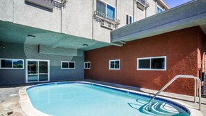 A swimming pool with a blue tiled edge, surrounded by a concrete deck. - Maywood Inn (Maywood)