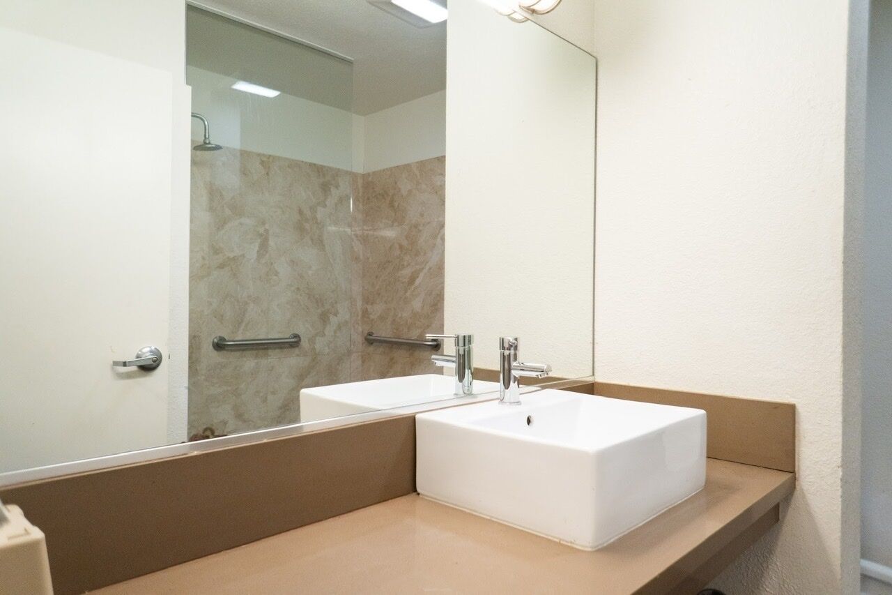 A bathroom with two white sinks, a large mirror, and a shower area.