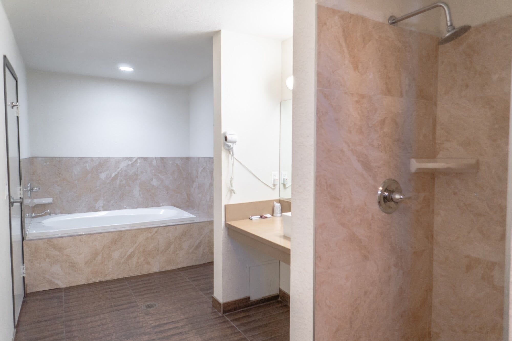A bathroom with a bathtub, a shower, and a vanity with a mirror.
