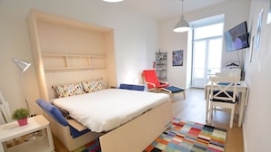 Ein modernes Schlafzimmer mit Bett, Schreibtisch, Stuhl und Fernseher.