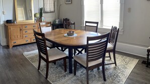 Een eetkamer met een houten tafel, zes stoelen, een houten dressoir en een grote spiegel.