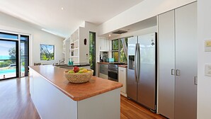 A modern kitchen with a central island, stainless steel appliances, and a view of the outdoors.