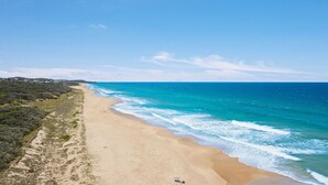 A beach with clear blue waters and a sandy shore.