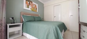Cozy retreat with a neatly made bed, bedside table, and wall-mounted art.