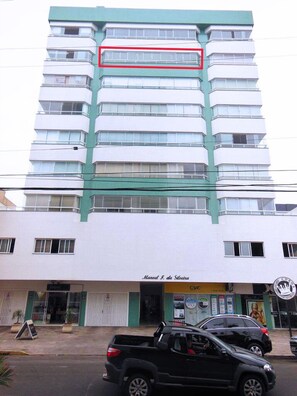 Stylish building with modern architecture and green accents, featuring balconies and a storefront.