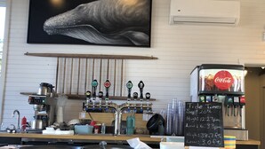 A bar with a mounted whale painting, a coffee machine, and a Coca-Cola dispenser. - Beautiful, private oceanfront cottage on the Bay of Fundy (Port Williams)