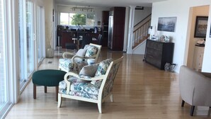 Een ruime woonkamer met een houten vloer, een bank, een fauteuil en een televisie.