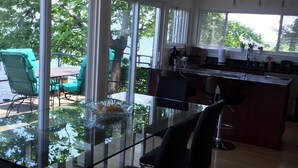 Een moderne keuken met een glazen eettafel, stoelen en uitzicht op de omgeving.