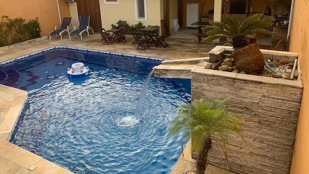 Ein Schwimmbad mit einer Springbrunnenanlage, umgeben von einer Terrasse mit Stühlen und einem Tisch.
