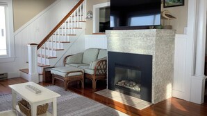A living room with a fireplace, a wooden staircase, and a comfortable seating area. - HAMPTON BEACH OCEANFRONT HOME SITUATED ON GREAT BOARS HEAD (Hampton)