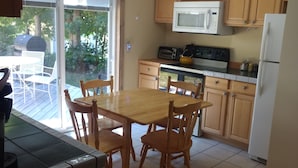 Una cocina con armarios de madera, una mesa de comedor con sillas, un microondas y un refrigerador.
