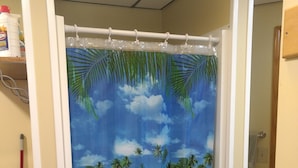 Un baño con cortina de ducha que muestra una escena de playa tropical.