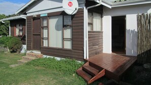 Una casa de dos pisos con antena parabólica, un muelle de madera y un pequeño porche delantero.