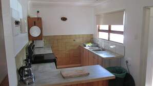 Una cocina pequeña con un fregadero, una estufa y una cafetera.