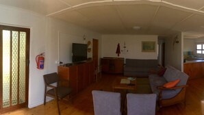 Un amplio espacio de sala con sofá, sillas, una mesa de comedor y una cocina al fondo.