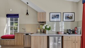 Una cocina moderna con armarios de madera, lavavajillas integrado, cafetera y juego de té en la encimera.