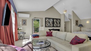 Un salón moderno con un sofá blanco, una mesa de centro de vidrio y un cojín rojo estampado.