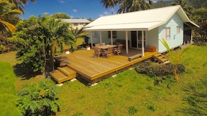 Uma casa com deck de madeira, móveis de exterior e um espaço coberto estilo pátio.