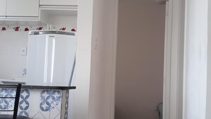 A kitchen with white cabinets, a refrigerator, and a tiled backsplash.