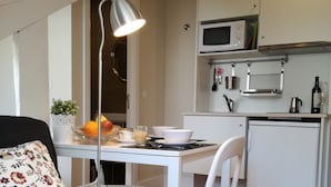 Een compacte leefruimte met een kitchenette, een eethoek en een bed.