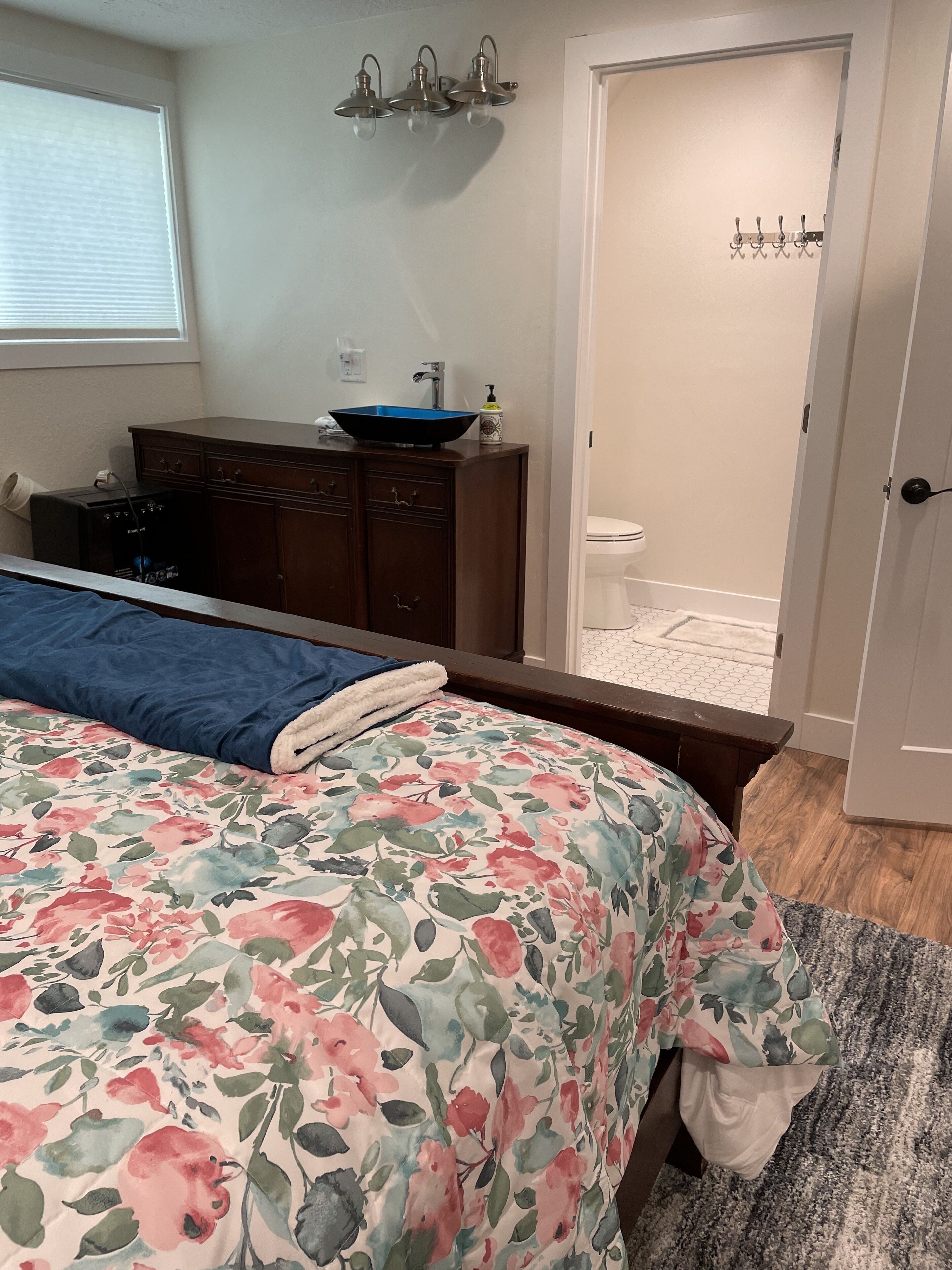A bedroom with a bed, dresser, and a bathroom door.