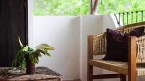 A wicker chair with a cushion and a potted plant on a woven table. - Acogedora palapa privada cerca de la playa. (Puerto Escondido)