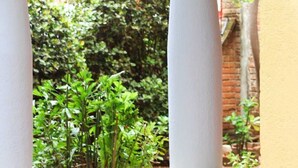 A courtyard with yellow and white columns, surrounded by greenery and a brick wall. - Acogedora palapa privada cerca de la playa. (Puerto Escondido)