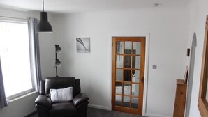 Una habitación con un sillón de cuero negro, una puerta de madera y un radiador.