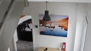 Una escalera que lleva a un dormitorio con una cama, una mesita de noche y una obra de arte colgada en la pared.