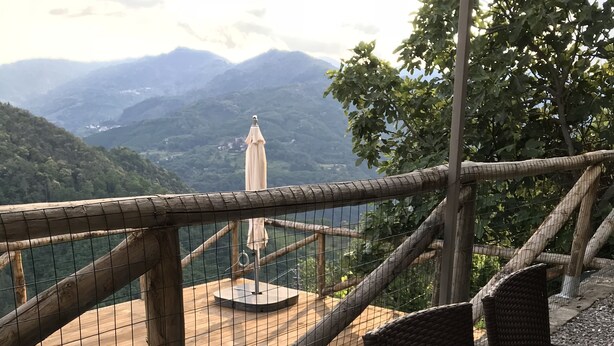 Outdoor seating with wicker chairs and a table, overlooking a pool and mountains.