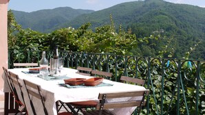 A table set outdoors with a mountain view, surrounded by a metal railing.