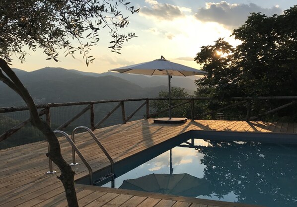Relax by the serene pool surrounded by a shaded wooden deck and tranquil surroundings.