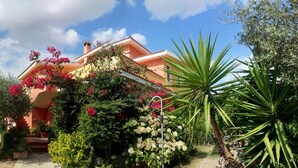 A house with a garden, a car parked in front, and a clear sky. - APARTMENT IN CASTIADAS BETWEEN SEA AND MOUNTAINS (cagliari)