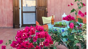 A building entrance with a wooden door, a wall-mounted clock, and a table with a bottle and glasses. - APARTMENT IN CASTIADAS BETWEEN SEA AND MOUNTAINS (cagliari)