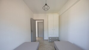 Een kamer met twee eenpersoonsbedden, een garderobe en een hanglamp.