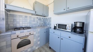 Een kleine keuken met een gasfornuis, oven, magnetron en koffiezetapparaat.