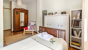 A bedroom with a bed, a wooden wardrobe, a chair, a bookshelf, and a wardrobe with a mirror. - Cottage in Amarante-Porto (Amarante)