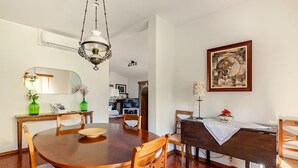 A dining area with a wooden table, chairs, a chandelier, a painting, and a television in the background. - Cottage in Amarante-Porto (Amarante)