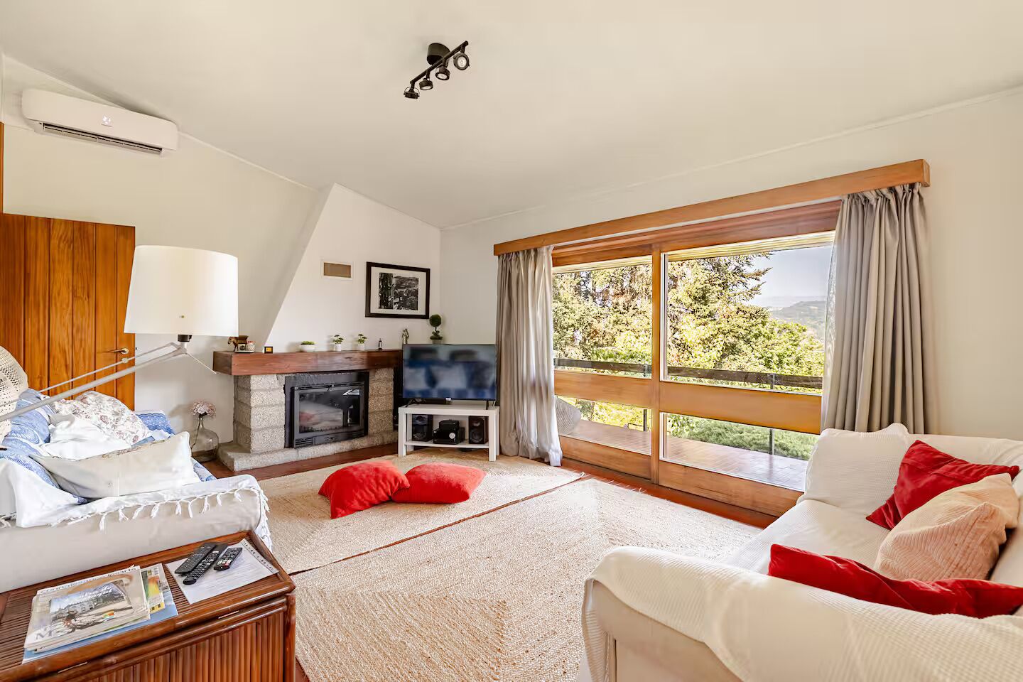 A living room with a fireplace, television, and large windows with curtains.