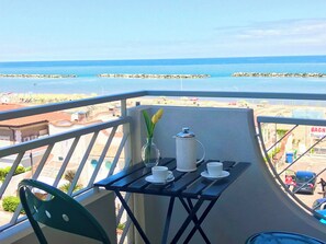 Uma varanda com mesa, cadeiras e vista para a praia e o mar.
