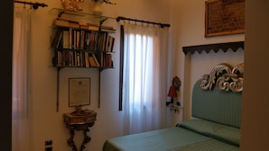 Un dormitorio con una cama, una estantería, un certificado enmarcado y un espejo decorativo.