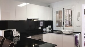 A modern kitchen with white cabinets, a black countertop, and stainless steel appliances. - Albir Apartment  in House with Community Pool, with the Garden (l'Alfàs del Pi)