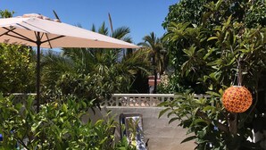 An outdoor seating area with a table and chairs, surrounded by lush greenery and a decorative hanging lantern. - Albir Apartment  in House with Community Pool, with the Garden (l'Alfàs del Pi)