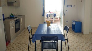 A compact kitchen with a dining area, a blue table, and chairs. - VILLA ALDA TWO ROOMS APARTMENT - Apartment with Enchanting View (Santa Cesarea Terme)