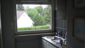 Een kleine keuken met een raam, een gootsteen en kastjes.