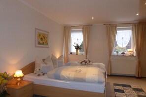 A bedroom with a bed, bedside table, lamp, and a window with curtains.
