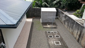 Eine Dachterrasse mit Metallbedachung, einer Betonwand und einem kleinen Gartenbereich mit Pflanzen.