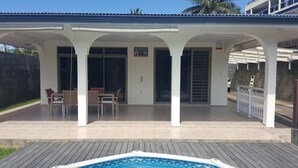 Eine überdachte Terrasse mit Pool, Sitzgelegenheit im Freien und einem Schild, das ein Restaurant anzeigt.