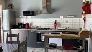 A modern kitchen with a microwave, coffee maker, and gas stove. There is a sink, cabinets, and a window.
