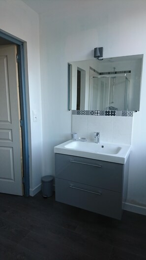 A bathroom with a white sink, a mirror with a decorative tile border, and a grey cabinet with drawers. - House For Rent Le Touquet / Cucq (Cucq)